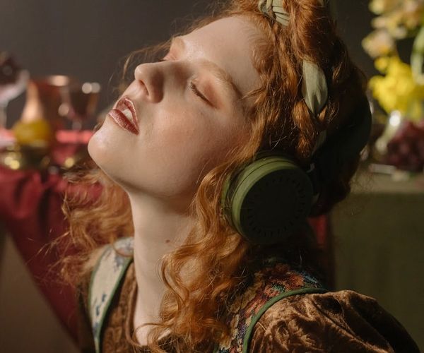 Person listening to guided session with headphones in a serene setting.